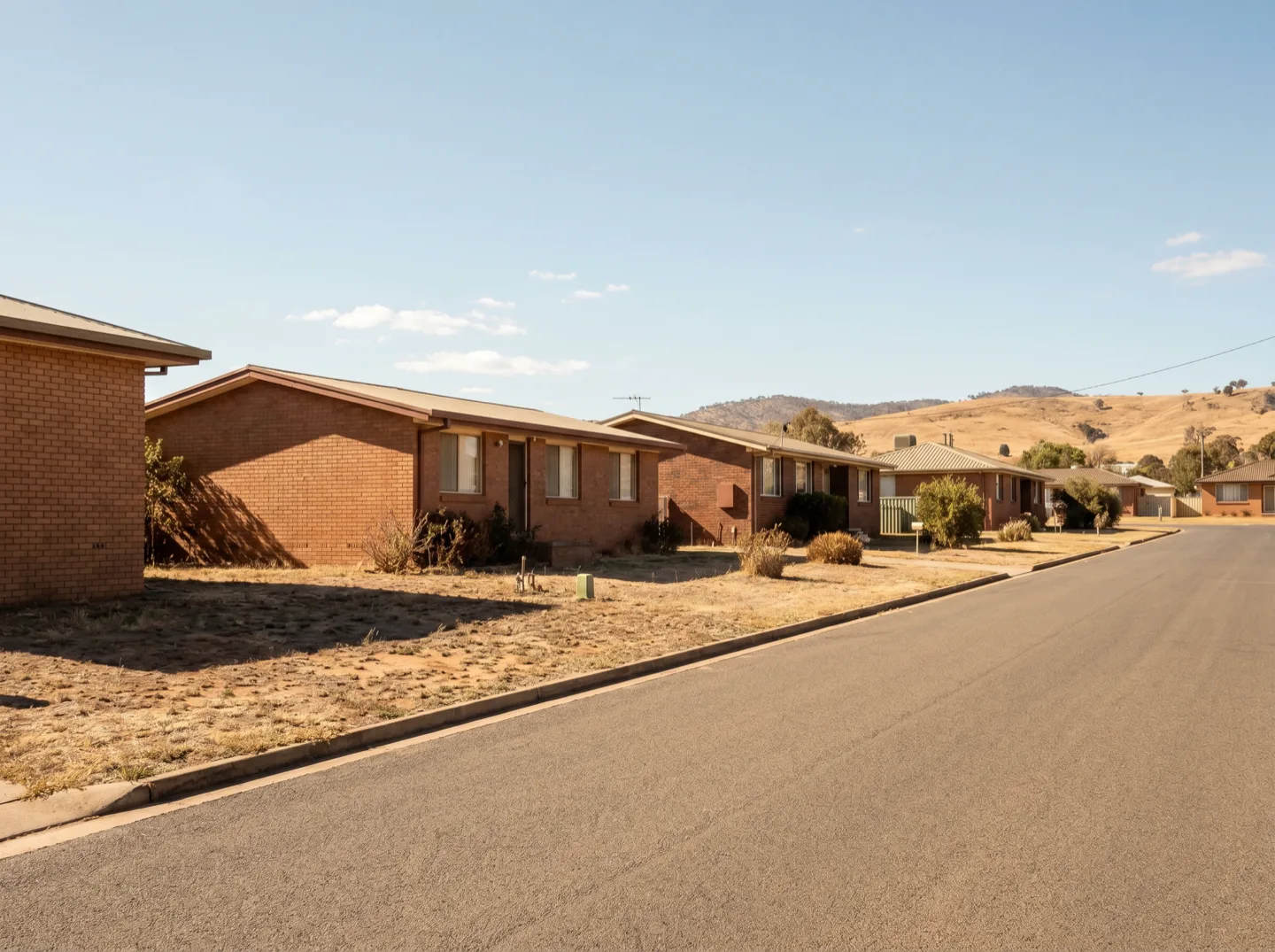 A quiet Muswellbrook street of brick-veneer homes in hard summer light